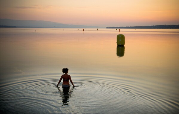 FILE - A woman takes a dip in Lake Geneva at sunrise in Geneva, Switzerland, July 21, 2013. (AP Photo/Anja Niedringhaus, File)