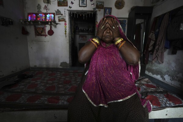 Shantaben Vanzara, wearing a wristwatch-style health monitor to study how heat affects vulnerable communities, wipes her face inside her house in Ahmedabad, India, Wednesday, April 2, 2025. (AP Photo/Ajit Solanki)