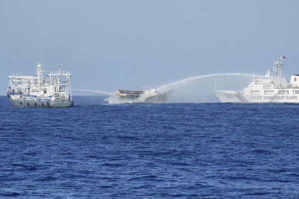 Philippine resupply vessel Unaizah May 4, center, is hit by two Chinese coast guard water canons as they tried to enter the Second Thomas Shoal, locally known as Ayungin Shoal, in the disputed South China Sea Tuesday, March 5, 2024. Chinese and Philippine coast guard vessels collided in the disputed South China Sea and four Filipino crew members were injured in high-seas confrontations Tuesday as Southeast Asian leaders gathered for a summit that was expected to touch on Beijing's aggression at sea. (AP Photo/Aaron Favila)