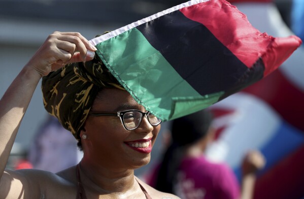 FILE - Crystal Baziel holds the Pan-African flag Monday, June 19, 2023, during Reedy Chapel A.M.E Church's annual Juneteenth Family Fun Day, in Galveston, Texas. Many Americans are celebrating Juneteenth, marking the day in 1865 when the last enslaved people in the U.S. learned they were free. For generations, Black Americans have recognized the end of one of history’s darkest chapters with joy, in the form of parades, street festivals, musical performances or cookouts. (Jennifer Reynolds/The Galveston County Daily News via AP, File)