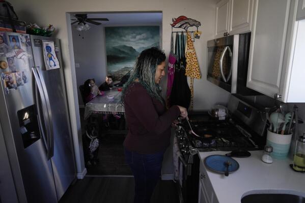 Betty Rivas prepares breakfast for her family Thursday, Feb. 23, 2023, in Commerce City, Colo. Rivas was startled by a letter telling her that the drinking fountains her 8-year-old used at school weren't safe. PFAS stories had been in the local news and the school district told families to use bottled water. (AP Photo/Brittany Peterson)