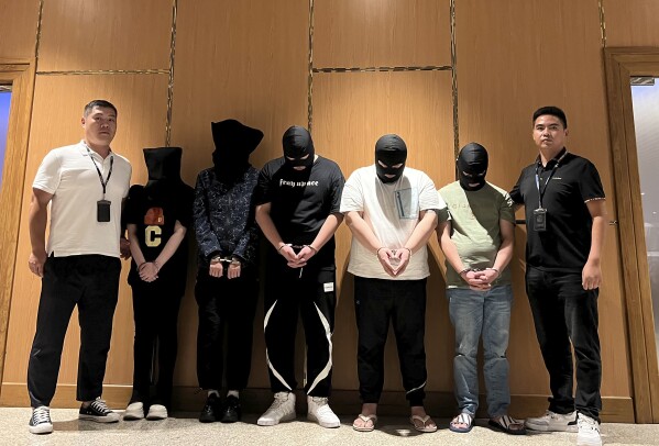 In this photo released by Xinhua News Agency, Myanmar police hand over five telecom and internet fraud suspects to Chinese police at Yangon International Airport in Yangon, Myanmar, Aug. 26, 2023. Tens of thousands of people, many of them Chinese, have been caught up in cyber scams based in Southeast Asia. Local and Chinese authorities have netted thousands of people in a crackdown on such schemes, but experts say they are failing to root out the local elites and criminal networks that are running the scams. (Chinese embassy in Myanmar/Xinhua via AP)