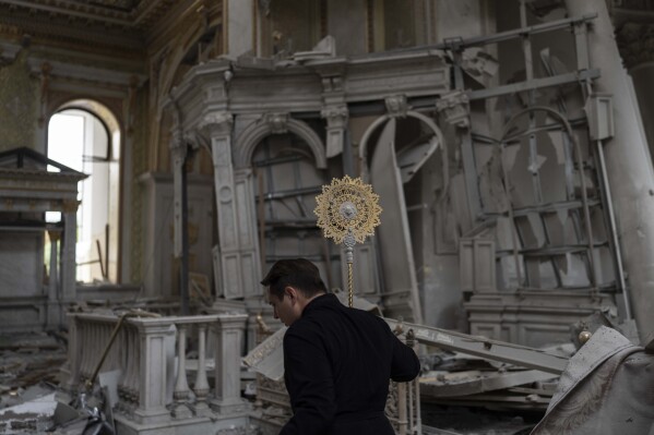 A church personnel salvages items while helping clean up inside the Odesa Transfiguration Cathedral after it was heavily damaged in Russian missile attacks in Odesa, Ukraine, Sunday, July 23, 2023. (AP Photo/Jae C. Hong)