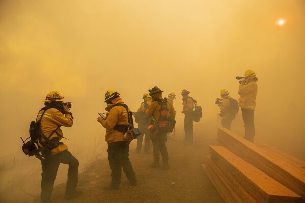 Firefighters with Cal Fire are enveloped in smoke as fire from the Green Fire passes by near homes on Hidden Glen Lane and Hidden Hills Road in Yorba Linda, Calif., Monday, Oct. 26, 2020. (Leonard Ortiz/The Orange County Register via AP)