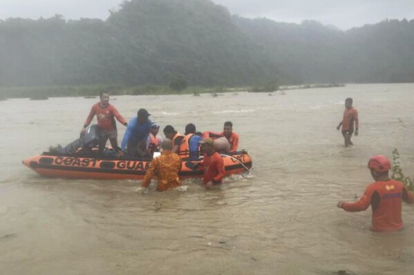 In this handout photo provided by the Philippine Coast Guard, rescuers use a rubberboat to evacuate quarry workers trapped in Naguilian, La Union province, northern Philippines on Wednesday, July 26, 2023. Typhoon Doksuri lashed northern Philippine provinces with ferocious wind and rain Wednesday, leaving several people dead and displacing thousands of others as it blew roofs off houses, flooded low-lying villages and triggered dozens of landslides, officials said. (Philippine Coast Guard via AP)