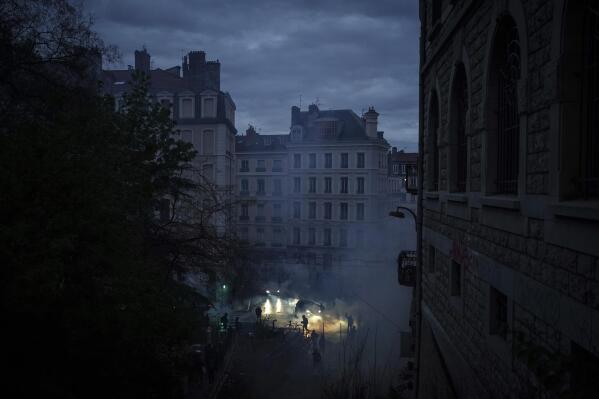 Demonstrators run in the tear gas during a demonstration in Lyon, central France, Friday, April 14, 2023. France's Constitutional Council on Friday approved an unpopular plan to raise the retirement age from 62 to 64, in a victory for President Emmanuel Macron after three months of mass protests over the legislation that have damaged his leadership. The decision dismayed or enraged critics of the pension plan, including protesters gathered outside Paris City Hall as the decision came down. (AP Photo/Laurent Cipriani)