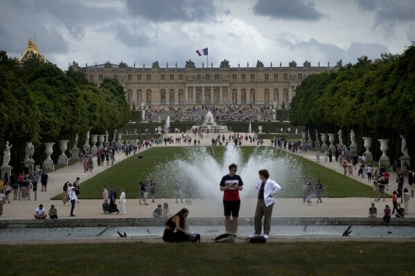 FILE - Visitors enjoy the Chateau de Versailles gardens, outside Paris, France, on July 15, 2023. France is rolling out the red carpet for King Charles III's state visit starting on Wednesday Sept. 20, 2023 at one of its most magnificent and emblematic monuments: the Palace of Versailles, which celebrates its 400th anniversary. (AP Photo/Christophe Ena, File)