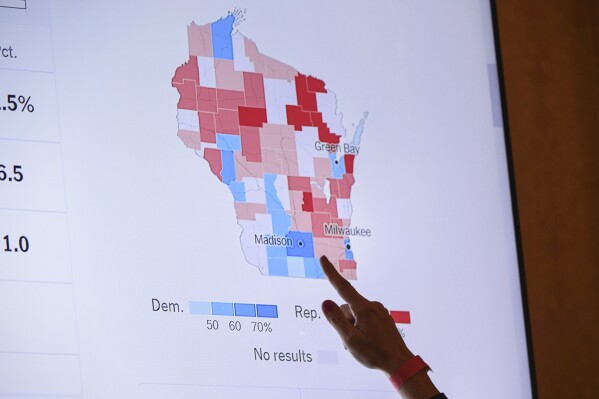 FILE - A supporter of Wisconsin Republican gubernatorial candidate Tim Michels points to the incoming state-wide data of the Wisconsin governor's race during an election night campaign event for Michels at the Italian Community Center, Nov. 8, 2022, in Milwaukee. When Republican candidates for president gather for their first debate Wednesday in Milwaukee, the spotlight will not only be on them, but Wisconsin's role as one of a shrinking handful of genuine battleground states. (AP Photo/Kenny Yoo, File)