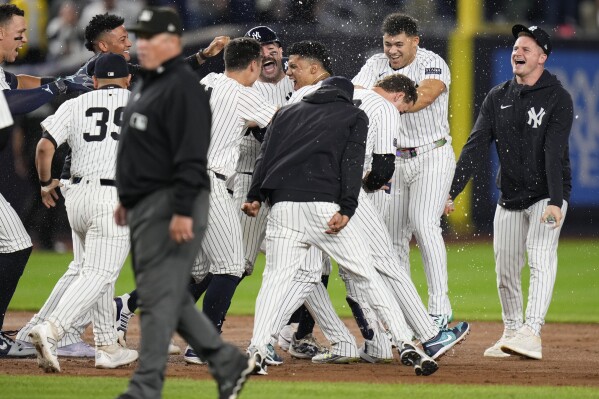 New York Yankees' Juan Soto, center, is mobbed by teammates after hitting the winning base hit during the 10th inning of a baseball game against the Boston Red Sox at Yankee Stadium, Thursday, Sept. 12, 2024, in New York. (AP Photo/Seth Wenig)