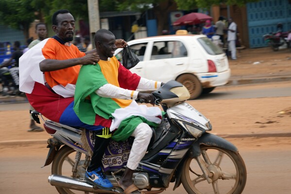 Nigerien men carrying Russian and Niger flags ride their motorcycle to an anti-French protest in Niamey, Niger, Friday, Aug. 11, 2023.The ECOWAS bloc said it had directed a 