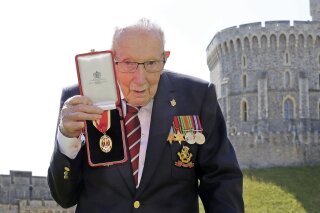 FILE - In this Friday, July 17, 2020 file photo, Captain Sir Thomas Moore poses for the media after receiving his knighthood from Britain's Queen Elizabeth, during a ceremony at Windsor Castle in Windsor, England. Tom Moore, the 100-year-old World War II veteran who captivated the British public in the early days of the coronavirus pandemic with his fundraising efforts, has been admitted to a hospital with COVID-19, his daughter said Sunday Jan. 31, 2021. (Chris Jackson/Pool Photo via AP, File)