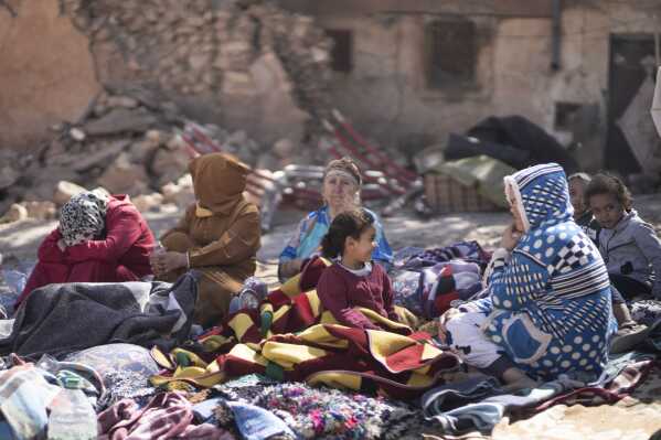 Families sit outside their destroyed homes after an earthquake in Moulay Brahim village, near Marrakech, Morocco, Saturday, Sept. 9, 2023. A rare, powerful earthquake struck Morocco late Friday night, killing more than 800 people and damaging buildings from villages in the Atlas Mountains to the historic city of Marrakech. But the full toll was not known as rescuers struggled to get through boulder-strewn roads to the remote mountain villages hit hardest. (AP Photo/Mosa'ab Elshamy)