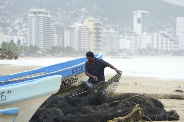 A fisherman maintains his net while his boat is off the water on Manzanillo beach as Hurricane Erick passes near Acapulco, Mexico, Thursday, June 19, 2025. (AP Photo/Fernando Llano)