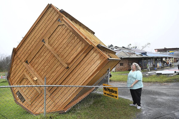 Jamie Coleman looks over at her storage building, Wednesday, April 3, 2024, that blew over in her yard along Route 60 in Hico, W.Va., during a storm that hit the area the day before. (Rick Barbero/The Register-Herald via AP)