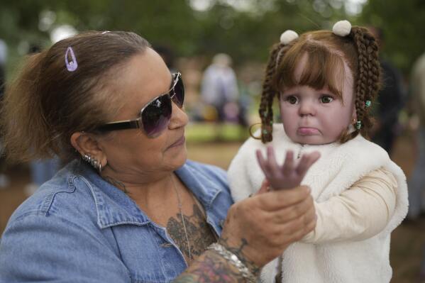 Nice Maria Santos holds her doll during a group gathering to bond and show off their hyper-realistic reborn baby dolls, in a park in Sao Paulo, Saturday, May 24, 2025. (AP Photo/Andre Penner)