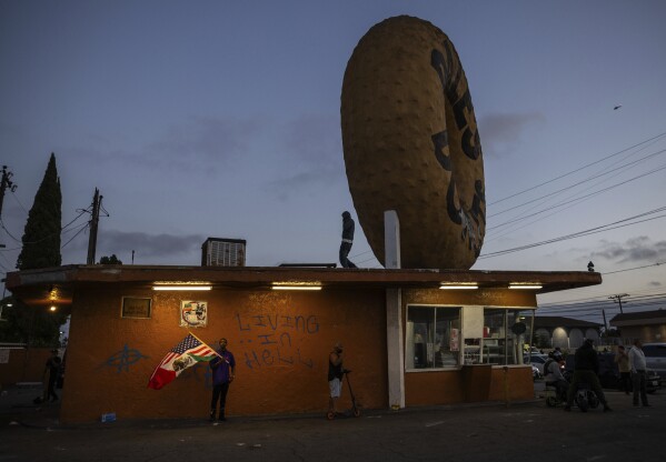 Spectators watch during a protest in Compton, Calif., Saturday, June 7, 2025, after federal immigration authorities conducted operations. (AP Photo/Ethan Swope)