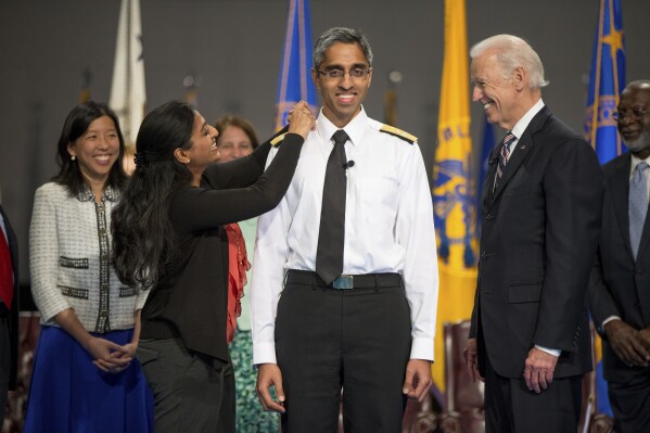 FILE - Then Vice President Joe Biden, right, watches as U.S. Surgeon General Vivek Murthy, center, receives an epaulet on his uniform by his sister Rashmi Murthy during a ceremonial swearing in ceremony in Conmy Hall at Fort Myer in Arlington, Va. on April 22, 2015. (APPhoto/Andrew Harnik, File)