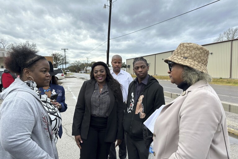 Darryl George, an 18-year-old high school junior, his mother, Darresha George, left, and his lawyer Allie Booker, center, speak with state Reps. Rhetta Bowers and Ron Reynolds following a court hearing in Anahuac, Texas, on Wednesday, Jan. 24, 2024. A judge ordered Wednesday that a trial be held next month to determine whether George can continue being punished by his district for refusing to change a hairstyle he and his family say is protected by a new state law. (AP Photo/Juan A. Lozano)