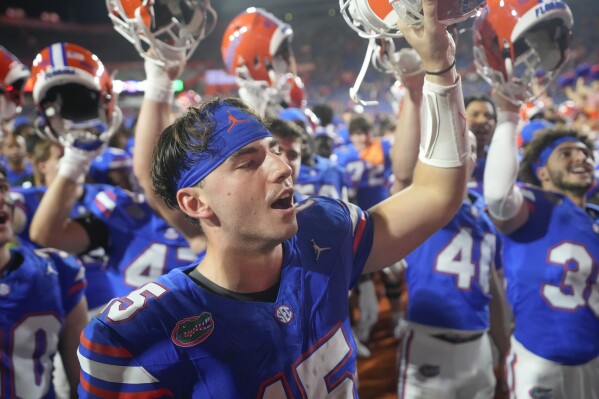 Florida quarterback Graham Mertz, foreground, celebrates with teammates after defeating Charlotte in an NCAA college football game, Saturday, Sept. 23, 2023, in Gainesville, Fla. (AP Photo/John Raoux)