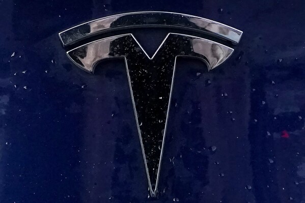 FILE - A Tesla electric vehicle emblem is affixed to a passenger vehicle Sunday, Feb. 21, 2021, in Boston. The lawyers who successfully argued that a massive pay package for Tesla CEO Elon Musk was illegal and should be voided have asked the presiding judge to award them company stock worth $5.6 billion as legal fees. The attorneys, who represented Tesla shareholders in the case decided in January, made the request of the Delaware judge in court papers filed Friday, March 1, 2024. (AP Photo/Steven Senne)