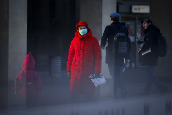 A woman wearing a face mask to help curb the spread of the coronavirus walks into the underpass under the street during sunset in Moscow, Russia, Wednesday, Dec. 2, 2020. Russia has registered a record number of coronavirus deaths for a second straight day. Currently, there is a country-wide mask mandate and mostly mild restrictions that vary from region to region. (AP Photo/Alexander Zemlianichenko)