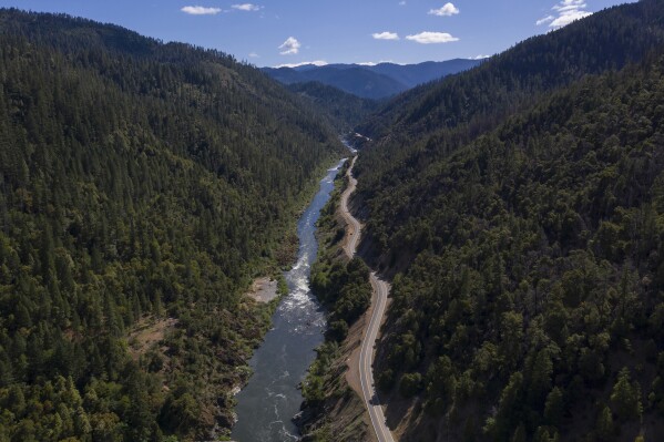 FILE - The Klamath River winds runs along state Highway 96 on June 7, 2021, near Happy Camp, Calif. Work has begun on removing four dams along the Klamath River, the largest dam removal project in history. All the dams are scheduled to come down by the end of 2024. (AP Photo/Nathan Howard, File)