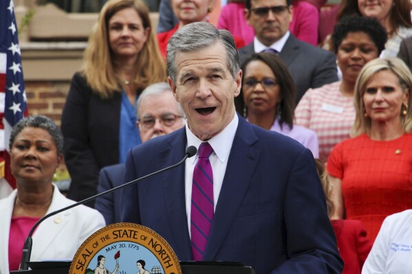 FILE - North Carolina Democratic Gov. Roy Cooper speaks March 27, 2023, outside the Executive Mansion in Raleigh, N.C., before signing a Medicaid expansion law that was a decade in the making. Cooper announced Friday, Sept. 22, 2023, that he would let the state budget bill that's reached his desk become law without his signature, opening the way for Medicaid coverage for 600,000 low-income adults, with some receiving the government health insurance soon. (AP Photo/Hannah Schoenbaum, File)