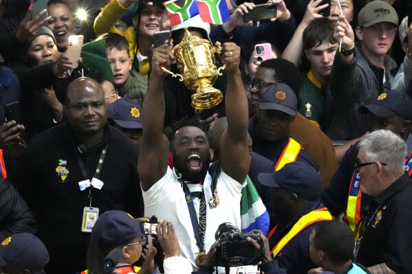 South Africa's Siya Kolisi holds the Webb Ellis trophy as fans welcome South Africa' Springbok team during their arrival at O.R Tambo's international airport in Johannesburg, South Africa, Tuesday Oct. 31, 2023, after the Rugby World Cup. (AP Photo/Themba Hadebe)
