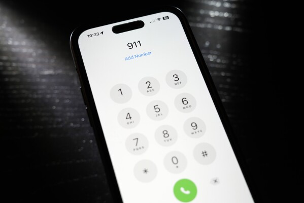 Emergency 911 number is dialed on a mobile phone, Thursday, April 18, 2024, in St. Louis. Law enforcement agencies in Nebraska, Nevada, South Dakota and Texas reported temporary outages to 911 services on Wednesday before saying hours later that services had been restored. (AP Photo/Jeff Roberson)