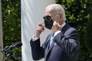 President Joe Biden removes his face mask as he arrives to speak in the Rose Garden of the White House in Washington, Wednesday, July 27, 2022. Biden ended his COVID-19 isolation after testing negative for the virus on Tuesday night and again on Wednesday. (AP Photo/Susan Walsh)