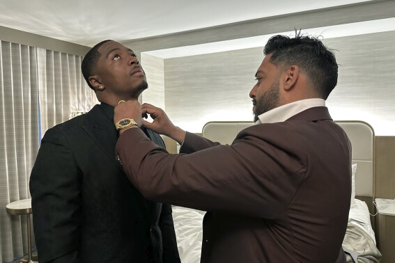 Ravi Punn, right, of Baynes + Baker, adjusts the collar on Toledo cornerback Quinyon Mitchell during a final suit fitting for the NFL football draft, Thursday, April 25, 2024 in Detroit. (AP Photo/Mike Householder)