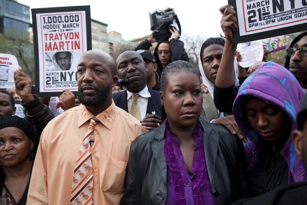 FILE - Trayvon Martin's parents, Tracy Martin, foreground left, and Sybrina Fulton, foreground center, and the family's lawyer, Bemjamin Crump, background center, participate in the Million Hoodie March for Trayvon Martin in New York's Union Square. The Black Lives Matter movement hits a milestone on Thursday, July 13, 2023, marking 10 years since its 2013 founding in response to the acquittal of the man who fatally shot the Black teenager. (AP Photo/John Minchillo, File)