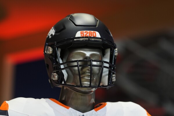 The number 5280 to mark the elevation of the city of Denver is displayed on the bumper of one of the helmets to go with the four new uniforms that the Denver Broncos NFL football team will wear starting in the upcoming season during a news conference at Empower Field at Mile High, Monday, April 22, 2024, in Denver. The update is the first major change to the team's uniforms since 1997. (AP Photo/David Zalubowski)