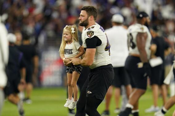 Baltimore Ravens linebacker Vince Biegel, right, carries his 3-year-old daughter Willow Biegel after the team's NFL football training camp practice at M&T Stadium, Saturday, July 30, 2022, in Baltimore. (AP Photo/Julio Cortez)