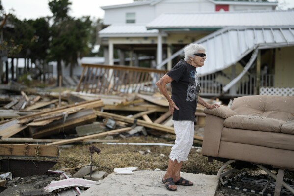 FILE - Tina Brotherton, 88, looks over the remains of her business, Tina's Dockside Inn, which was completely destroyed in Hurricane Idalia, as was Brotherton's nearby home, in Horseshoe Beach, Fla., Sept. 1, 2023. More Americans believe they've personally felt the impact of climate change because of recent extreme weather according to new polling from The Associated Press-NORC Center for Public Affairs Research. (AP Photo/Rebecca Blackwell, File)