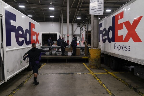 FILE - FedEx delivery trucks are parked next to a conveyor belt while being loaded with packages for delivery at the FedEx regional hub at the Los Angeles International Airport in Los Angeles, Dec. 7, 2021. Carriers like the U.S. Postal Service, FedEx and United Parcel Service have capacity to meet projected demand this holiday season, which is cheery news for shippers and shoppers alike. (AP Photo/Jae C. Hong)