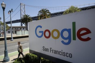 FILE - In this May 1, 2019, file photo a man walks past a Google sign outside with a span of the Bay Bridge at rear in San Francisco. A group of states are expected to announce an investigation into Google on Monday, Sept. 9, to investigate whether the tech company has become too big. (AP Photo/Jeff Chiu, File)
