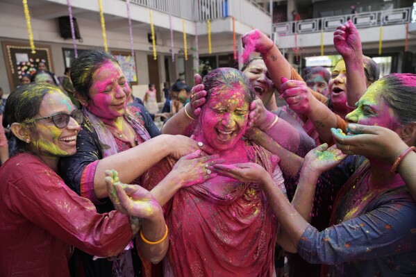 FILE - Teachers apply colored powder on another as they celebrate Holi, the Hindu festival of colours, at a school in Ahmedabad, India, Thursday, March 17, 2022. (AP Photo/Ajit Solanki, File)