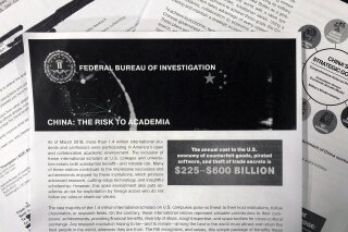 This Oct. 4, 2019 photo shows a copy of an FBI pamphlet and related emails. The Trump administration says it will soon require Chinese officials in the U.S. to notify the State Department ahead of any contacts they plan to have with American educators, researchers and local and state governments. (AP Photo)