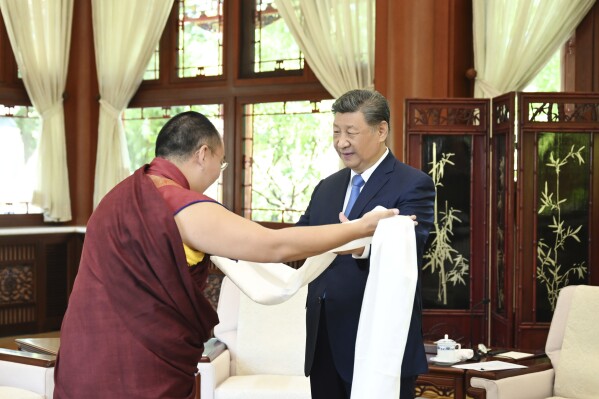 In this photo released by Xinhua News Agency, Gyaltsen Norbu, the Chinese government-appointed 11th Panchen Lama, presents a hada to Chinese President Xi Jinping at the Zhongnanhai leadership compound in Beijing on Friday, June 6, 2025. (Xie Huanchi/Xinhua via AP)