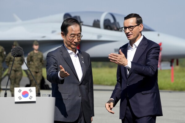 South Korean Prime Minister Han Duck-Soo, left, and his Polish host, Prime Minister Mateusz Morawiecki, right, talk prior to a press conference following talks on regional security and and the examination of the FA-50 fighter jets that Poland recently bought from South Korea, along with other military equipment, at an air base in Minsk Mazowiecki, eastern Poland, Wednesday, Sept. 13, 2023. Han was in Poland for talks on regional security amid war in neighboring Ukraine, and also to discuss military and nuclear energy cooperation. (AP Photo/Czarek Sokolowski)