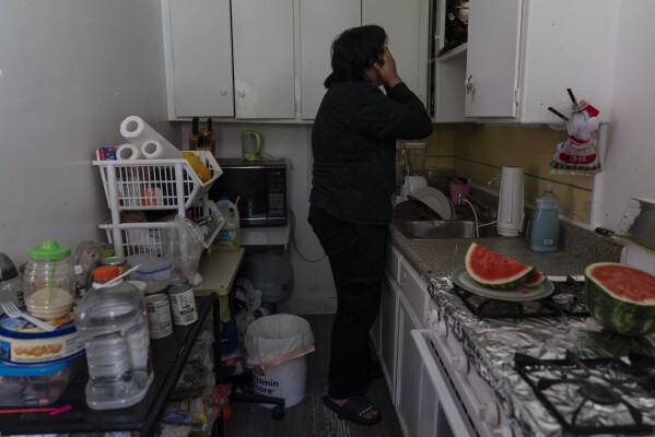 Deneffy Sánchez, 15, wipes his face in the kitchen of a studio apartment his family shares with two roommates in Los Angeles, Saturday, Sept. 9, 2023. It's the third apartment his family has shared with strangers this year as they try to avoid homeless shelters. Deneffy is one of 13,000 homeless students in Los Angeles Unified School District. (AP Photo/Jae C. Hong)