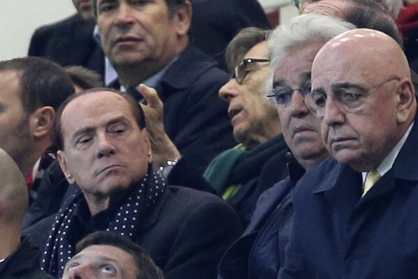 FILE - In this Nov. 6, 2012 file photo, Silvio Berlusconi, left, sits next to businessman Flavio Briatore, and former AC Milan CEO Adriano Galliani, right as he attends a match t the San Siro stadium in Milan, Italy. Italy’s former prime minister and right-wing leader Silvio Berlusconi has tested positive to coronavirus after a precautionary check, his press office said on Wednesday, Sept. 2, 2020. The three-time-premier and media tycoon had been recently seen with his old-time friend and businessman Flavio Briatore, who was recently hospitalized after testing positive to Covid-19 last month. Berlusconi had tested negative at the time. (AP Photo/Antonio Calanni)
