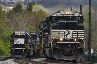 FILE - A Norfolk Southern freight train passes a train on a siding as it approaches a crossing in Homestead, Pa., Wednesday, April 27, 2022. Three of the 12 unions negotiating with the nation's biggest freight railroads reached a tentative deal, Monday, Aug. 29, 2022, which will deliver 24% raises in line with what a special presidential panel of arbitrators recommended earlier this month to resolve the stalemate before a strike could happen. (AP Photo/Gene J. Puskar, File)
