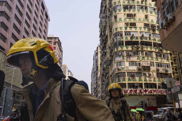 Firefighters walk past a building called New Lucky House where a fire started in Hong Kong, Wednesday, April 10, 2024. (AP Photo/Louise Delmotte)