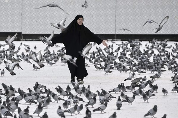 A Muslim pilgrim plays with pigeons outside the Grand Mosque during the annual hajj pilgrimage in Mecca, Saudi Arabia, Tuesday, June 3, 2025. (AP Photo/Amr Nabil)