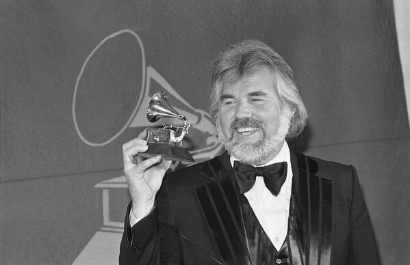 FILE- In this Feb. 28, 1980 file photo, Kenny Rogers holds a Grammy Award he received during presentation in Los Angles.  Rogers, who embodied “The Gambler” persona and whose musical career spanned jazz, folk, country and pop, has died at 81. A representative says Rogers died at home in Georgia on Friday, March 20, 2020. (AP Photo/McLendon, File)