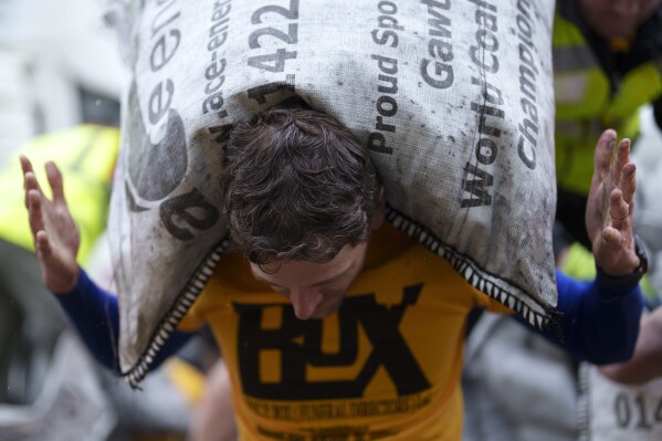 A contestant loads a 50kg bag of coal onto his shoulders during the World Coal Carrying Championships in Ossett, West Yorkshire, England, Monday, April 21, 2025. (AP Photo/Jon Super)