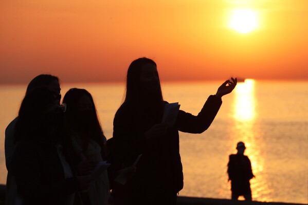 FILE - A parishioner is silhouetted against the rising sun as she prays during an Easter sunrise service held by Park Community Church Sunday, April 4, 2021, at North Avenue Beach in Chicago. On Easter morning, many Christians wake before dawn. They will celebrate their belief in the resurrection of Jesus, the son of God, as the sun rises. (AP Photo/Shafkat Anowar, File)