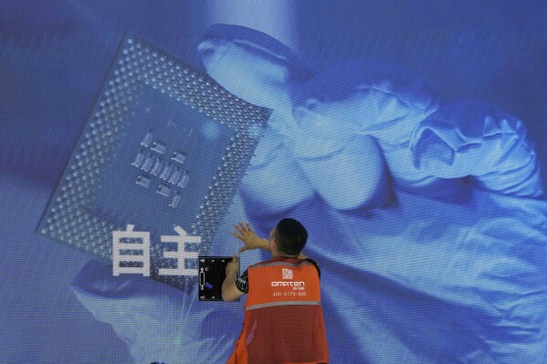 A worker checks the display panel showing a computer chip and the Chinese words for "Independence" at the booth for Chinese supercomputer manufacturer Sugon during the World AI Conference in Shanghai, Wednesday, July 5, 2023. China's government appealed to Japan on Monday, July 24, not to disrupt the semiconductor industry after curbs on exports of Japanese chip-making technology took effect, adding to technology restrictions Washington and its allies have imposed on China on security grounds. (AP Photo/Ng Han Guan)